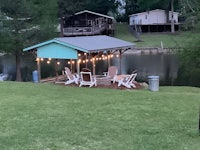 a gazebo with chairs and a fire pit next to a lake